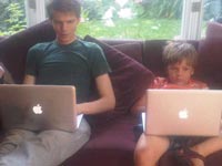 My eldest and youngest sons on the chesterfield staring at MacBooks